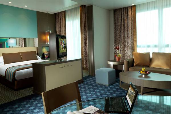 Innenansicht der Suite im Park Rotana Abu Dhabi Hotel mit Bett, Fernseher, Tisch, Laptop und Zeitschriften
