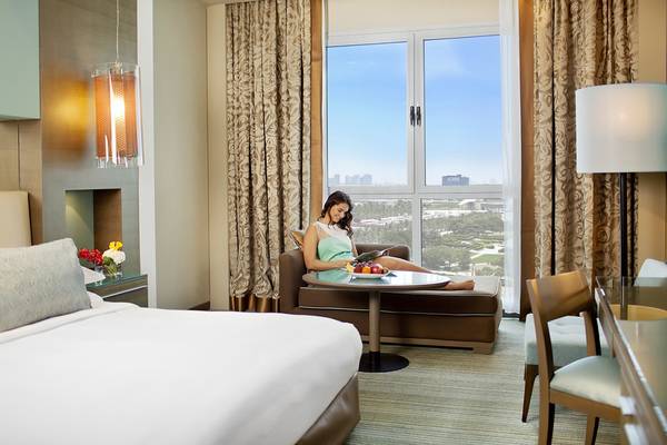 Frau im Hotelzimmer von Park Rotana Abu Dhabi vor einem grossen Fenster