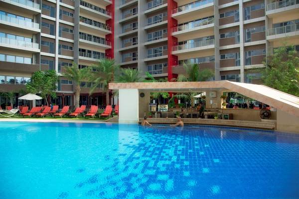 Außenansicht des Swimmingpools im Park Rotana Abu Dhabi Hotel mit Loungestühlen und Sonnenschirmen.