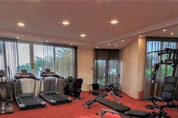 Fitnessraum im Elea Beach Hotel mit roten Teppichboden und Trainingsgeräten.