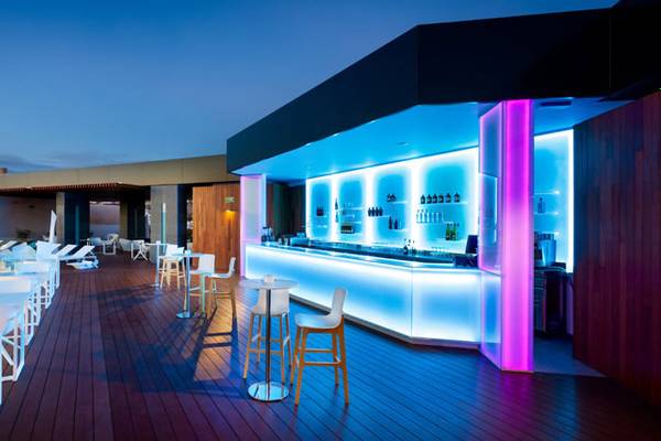 Hotelbar-Terrasse bei Nacht mit beleuchteten Säulen und Tischen