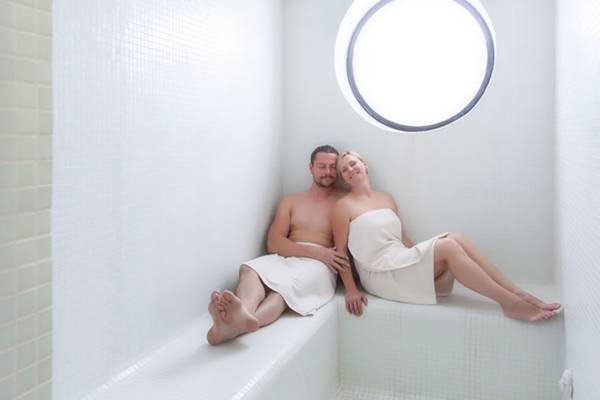 Ein Paar sitzt in einem Dampfbad im Tigotan Lovers & Friends Hotel.