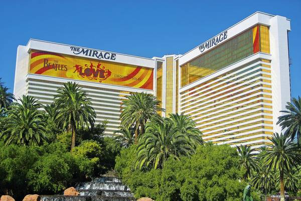Außenansicht des Mirage Hotel & Casino mit einem Beatles-Werbebanner und Wasserfall davor.
