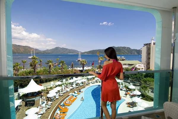 Frau in rotem Kleid auf dem Balkon des Casa De Maris Spa & Resort mit Blick auf den Pool und das Meer