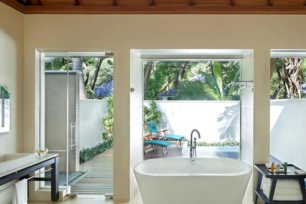 Badezimmer im Hilton Seychelles Labriz Resort & Spa mit Badewanne, Dusche und Blick auf den Garten.