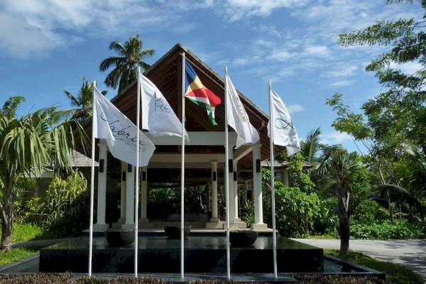 Eingang des Hilton Seychelles Labriz Resort & Spa mit mehreren Flaggen vor dem Gebäude.