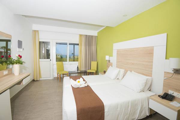 Eurovillage Achilleas Hotelzimmer mit zwei Betten, grünen Wänden und einem Blick auf das Meer.