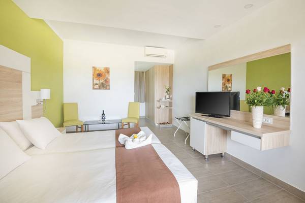 Doppelzimmer im Eurovillage Achilleas mit zwei Betten, einem Schreibtisch, einem Fernseher und einem grünen Dekor.