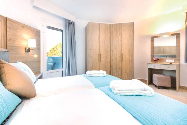 Zwei Betten mit blauen Decken und weißen Laken in einem Schlafzimmer im Eurovillage Achilleas Hotel.