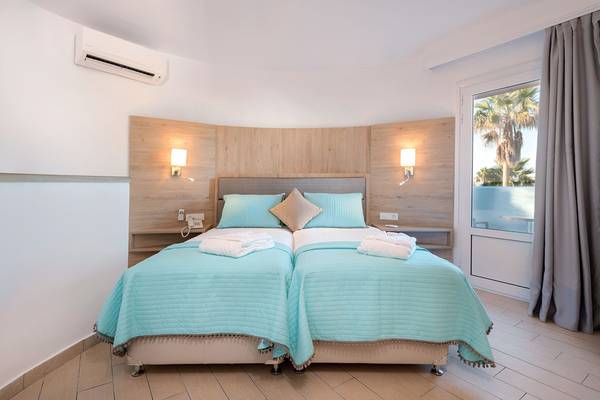 Doppelbett-Zimmer im Eurovillage Achilleas Hotel mit blauen Laken und Kissen.