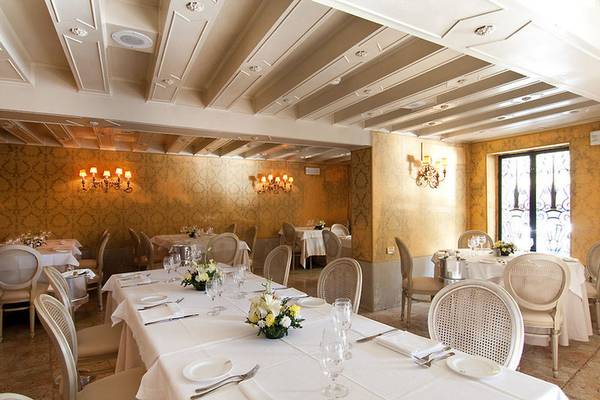 Innenansicht des CHC Continental, BW Premier Collection Restaurants mit eleganten Esstischen, goldenen Wandverkleidungen und kristallenen Kronleuchtern.