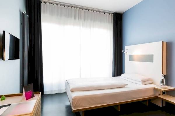 Ein modernes Hotelzimmer mit einem Bett, Fernseher und einem Tisch.