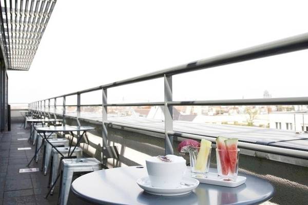 Dachterrasse des Ku Damm 101 Hotels mit Tischen, Stühlen und Getränken