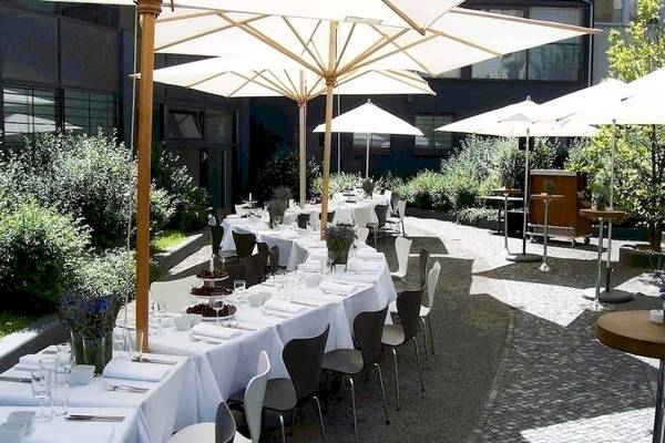 Außenbereich des Ku Damm 101 Hotels mit gedeckten Tischen und Schirmen