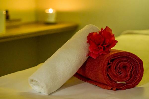 Ein rotes und ein weißes Handtuch mit einer roten Blume auf einem Bett.