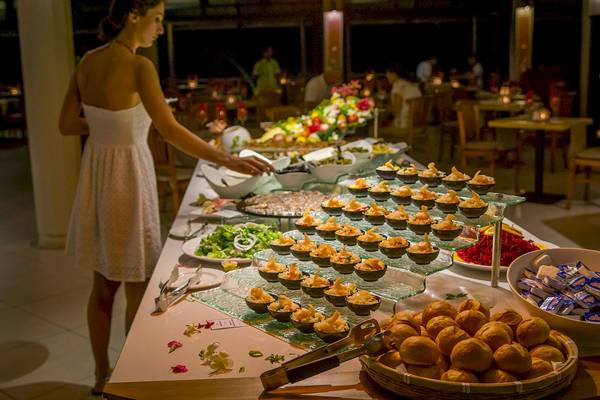 Buffet-Tisch im Le Peninsula Bay Beach Resort & Spa mit verschiedenen Gerichten und einer Frau in einem weißen Kleid.
