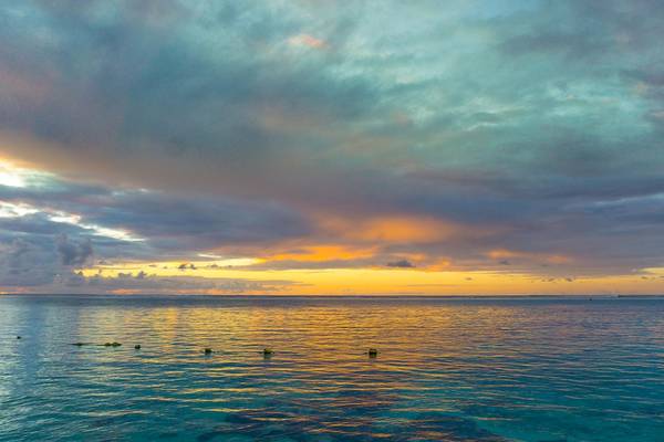 Sonnenuntergang am Le Peninsula Bay Beach Resort & Spa mit einem blauen Ozean und wolkenreichem Himmel.