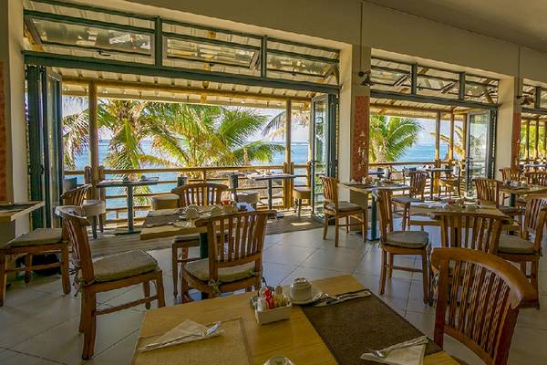 Innenansicht des Restaurants im Le Peninsula Bay Beach Resort & Spa mit Blick auf das Meer.