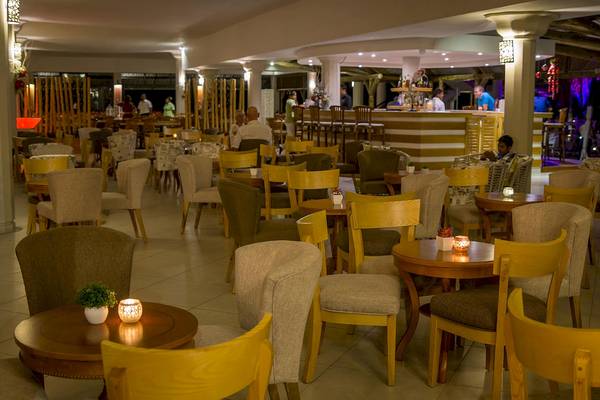 Innenbereich des Le Peninsula Bay Beach Resort & Spa mit vielen Stühlen und Tischen, an denen Gäste sitzen und essen.