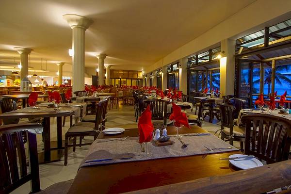 Innenansicht des Restaurants im Le Peninsula Bay Beach Resort & Spa mit gedeckten Tischen und Blick auf den Ozean.