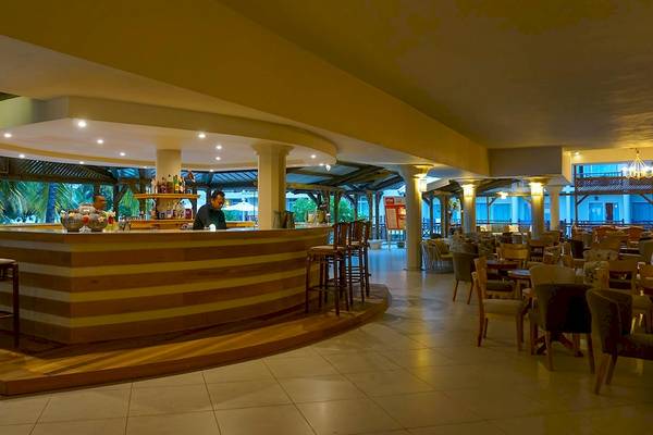 Innenansicht der Bar im Le Peninsula Bay Beach Resort & Spa Hotel mit Barkeeper und Gästen.