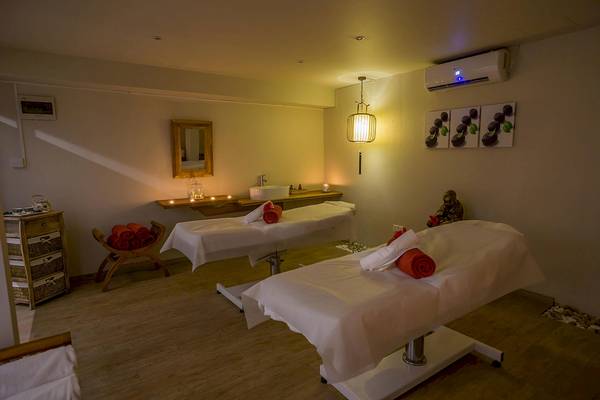 Massageraum im Le Peninsula Bay Beach Resort & Spa mit zwei Massagetischen und dekorativen Elementen.