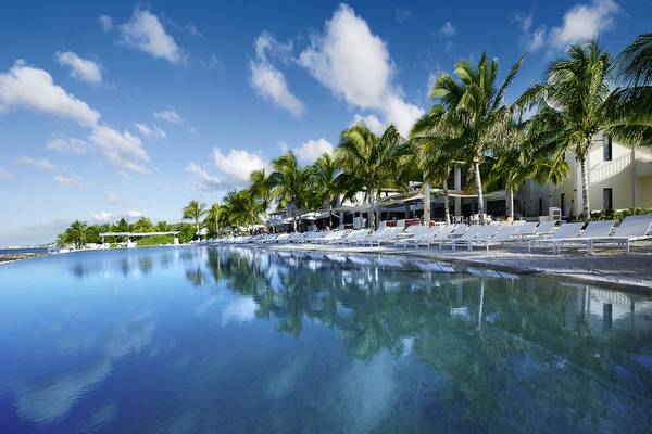 Pool mit weißen Sonnenliegen und Palmen im Papagayo Beach Hotel & Resort auf Curaçao