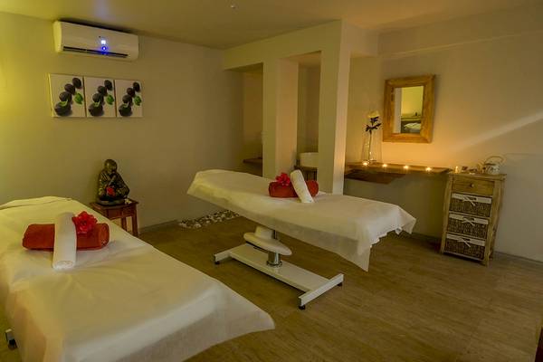 Massageraum im Le Peninsula Bay Beach Resort & Spa mit zwei Massagetischen, Deko und einer Statue.