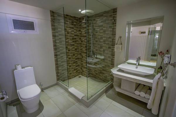 Badezimmer im Le Peninsula Bay Beach Resort & Spa mit Glasdusche, Toilette, Waschbecken und Spiegel.