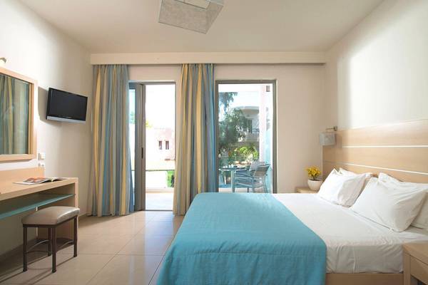 Corissia Princess Hotel Zimmer mit Bett, Schreibtisch und Balkon.