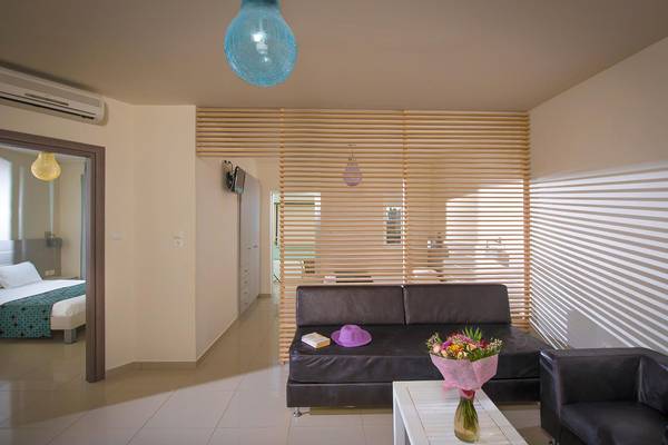 Wohnbereich des Corissia Princess Hotels mit Couch, Tisch und Bett im Hintergrund.