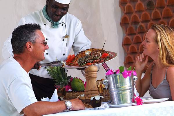 Ein Koch serviert Gästen ein Gericht im Pinewood Beach Resort & Spa.