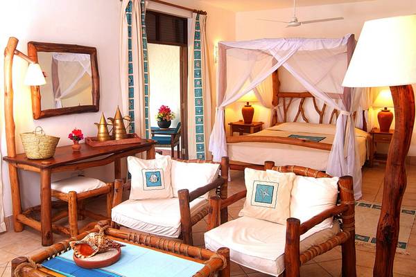 Schlafzimmer im Pinewood Beach Resort & Spa mit Bett, Nachttischen, Stühlen und Dekor.
