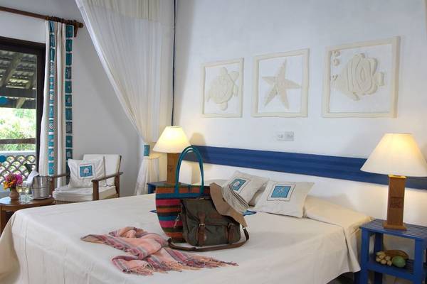 Schlafzimmer im Pinewood Beach Resort & Spa mit einem Bett, Dekor und Meerestier-Kunstwerken an der Wand.