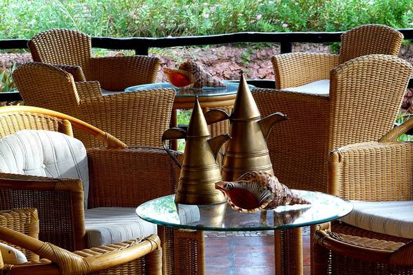 Terrasse des Pinewood Beach Resorts mit Korbstühlen und Geschirr.