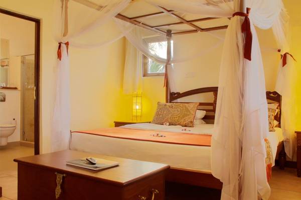 Schlafzimmer im Pinewood Beach Resort & Spa mit einem Himmelbett, Bettwäsche und Kissen.