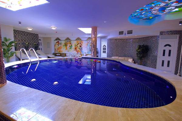 Ein ovaler Pool im Dalyan Resort Hotel mit bunten Fliesen und einer bunten Glasdecke.