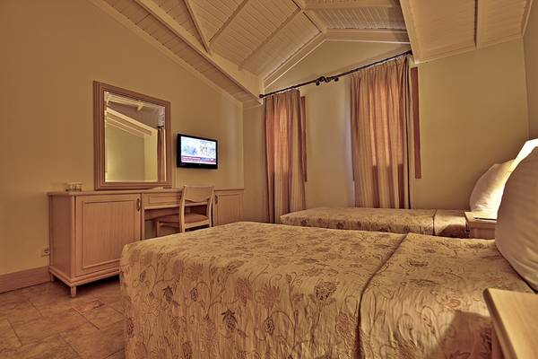 Doppelzimmer im Dalyan Resort Hotel mit zwei Betten, Fernseher, Schreibtisch und Spiegel.