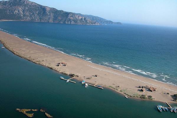 Luftaufnahme des Dalyan Resort Hotels zeigt eine Küste mit Bergen und einem langen Sandstrand.