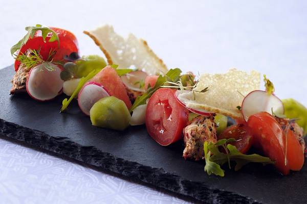 Ein Gericht im Southern Sun Abu Dhabi mit Tomaten, Radieschen und grünem Gemüse auf einem schwarzen Teller.