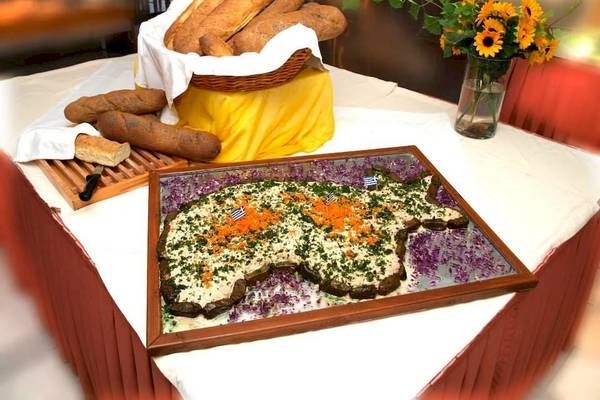 Ein Tisch mit einem Brotkorb und einem griechischen Gericht in Form einer Karte.