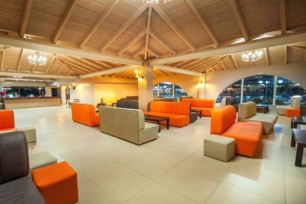 Lobby des Akti Beach Club Hotels mit orangefarbenen Sofas und weißen Fliesenboden.