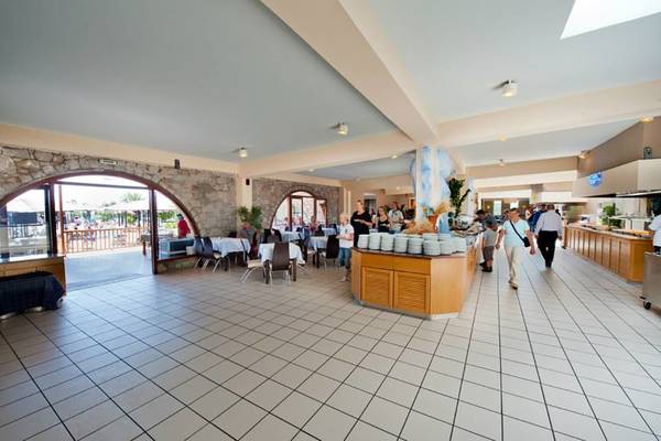 Innenansicht des Restaurants im Akti Beach Club Hotel mit Gästen, die an Tischen sitzen und Speisen serviert werden.