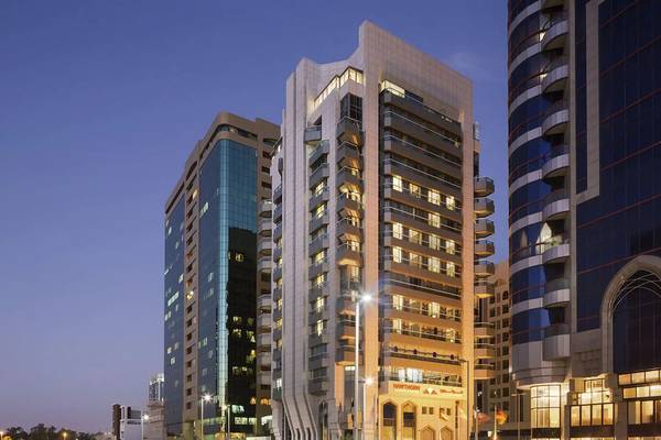 Abendansicht des Hawthorn Suites Abu Dhabi Hotels, das zwischen anderen Hochhäusern in der Stadt steht.