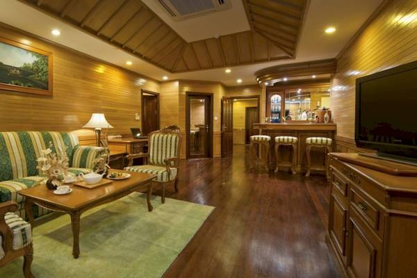 Das Wohnzimmer des Royal Island Resort & Spa mit Holzwänden, einem grünen Sofa, einem Tisch und einer Fernseher.