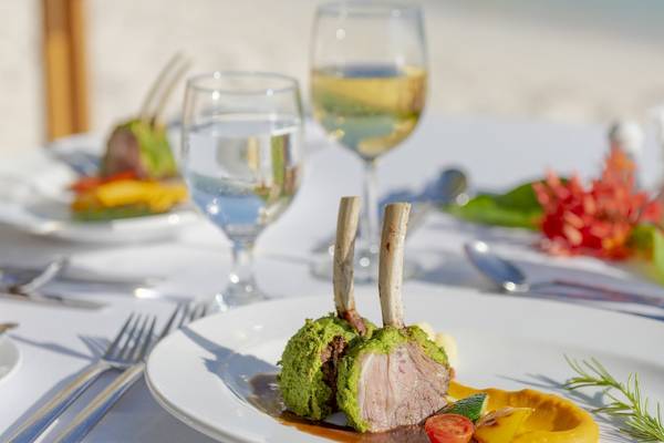 Eine Mahlzeit im Royal Island Resort & Spa mit Gerichten, Gläsern und Dekoration am Strand.