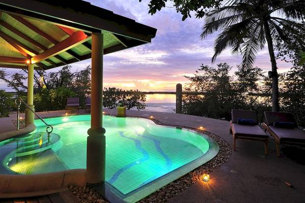 Abendlicher Blick auf den Infinity-Pool des Royal Island Resort & Spa mit beleuchteten Stufen und Lounge-Sesseln.