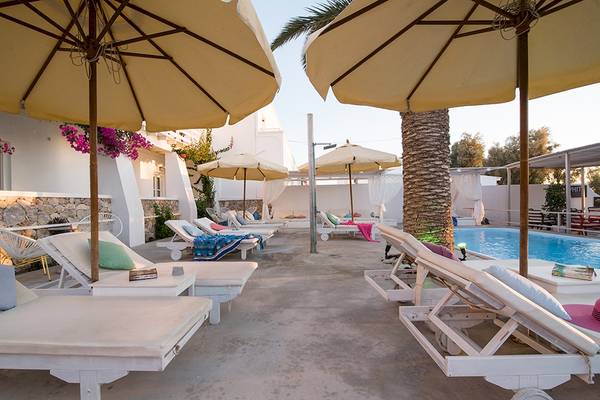 Lounge-Bereich des Beach Boutique Hotels mit weißen Liegen, gelben Sonnenschirmen und einem Pool.