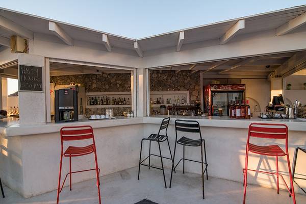 Cocktailbar im Beach Boutique Hotel mit roten Stühlen und Steinmauer