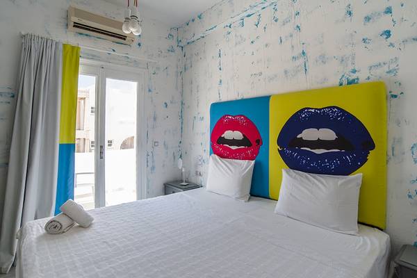 Schlafzimmer im Beach Boutique Hotel mit buntem Wandbild und weißem Bett.